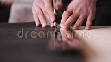 制革工人正在用剃刀和米尺剪黑色的皮
